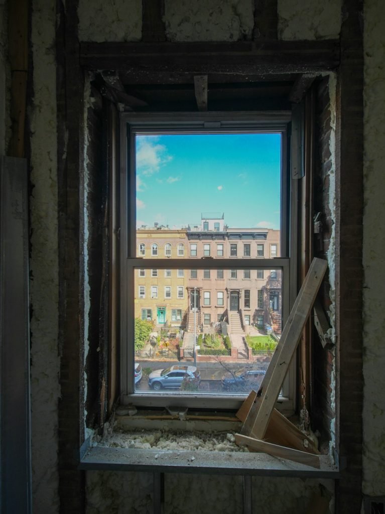 A three-story brownstone stands in mid-transformation, captured at the raw and honest “before” stage of a full interior renovation. These images document a moment that usually disappears once the walls are closed and the finishes are installed — exposed framing, stripped ceilings, rough staircases, and open corridors that reveal the building’s original structure and hidden history. Light spills in through skylights and tall windows, cutting through layers of dust and unfinished surfaces, creating a quiet contrast between decay and renewal. The space feels both industrial and intimate: narrow